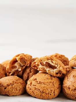 pile of cookie amaretti on white marble background - traditional Italian Sardinian pastry. Amaretti biscuit cookies made from almond or apricot kernels with copy space. Vertical