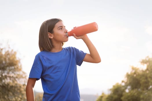girl drinking water during her training, concept of sport in nature for children and healthy lifestyle