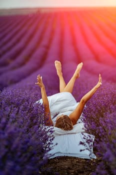 Woman lavender field. A middle-aged woman lies in a lavender field and enjoys aromatherapy. Aromatherapy concept, lavender oil, photo session in lavender.