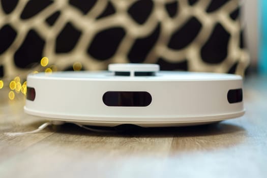 White robot vacuum cleaner cleans the apartment automatically. Smart Home selective focus