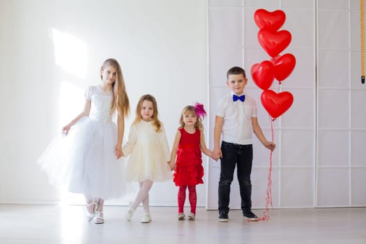 four children standing with balloons in bright holiday room