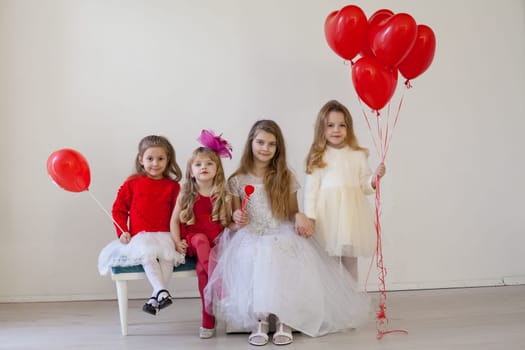 a four children with red balloons sitting in a holiday room