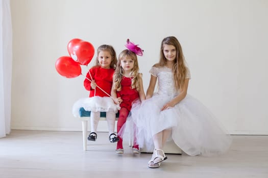 a three children with red balloons sitting in a holiday room