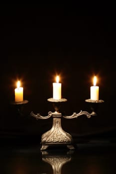 Nice vintage candlestick with lighting candles on dark background