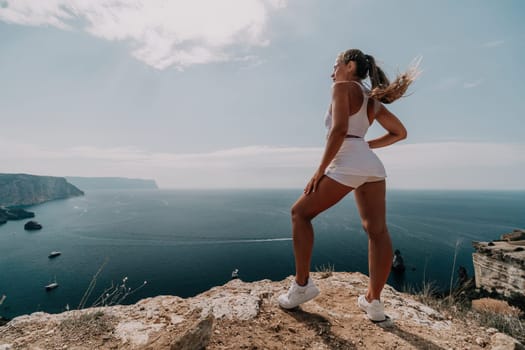 Middle aged well looking woman with black hair doing Pilates with the ring on the yoga mat near the sea on the pebble beach. Female fitness yoga concept. Healthy lifestyle, harmony and meditation.