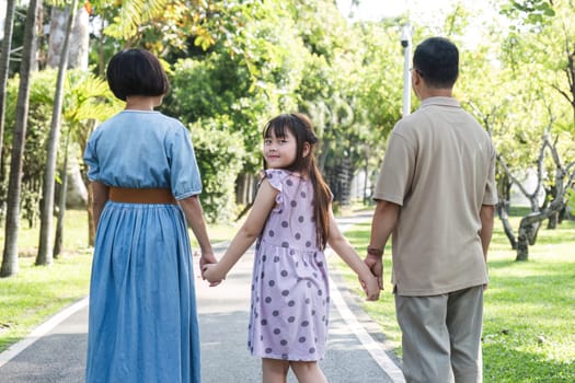 Kind-hearted Asian senior grandparent Warm and happy enjoying a stroll through the park with their adorable little granddaughter. On a clear day together lovely family.