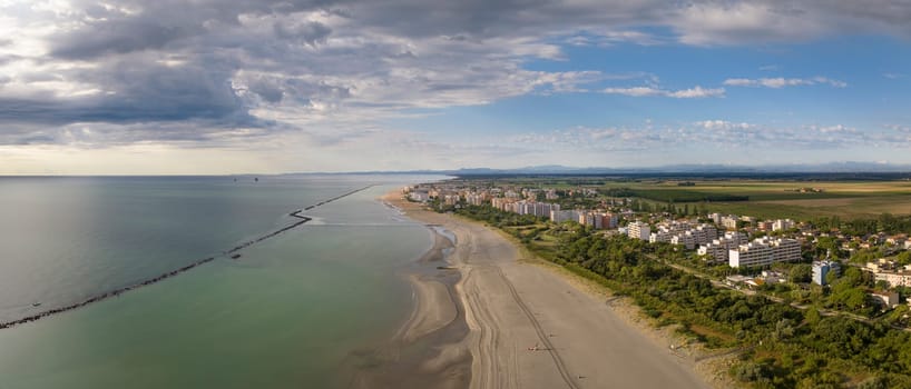 Drone shot of sandy beach with umbrellas and gazebos.Summer vacation concept.Lido Adriano town,Adriatic coast, Emilia Romagna,Italy.
