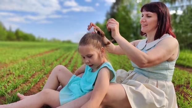 Happy mother and daughter enjoying rest, playing and fun on nature in green field. Woman and girl resting outdoors in summer or spring day