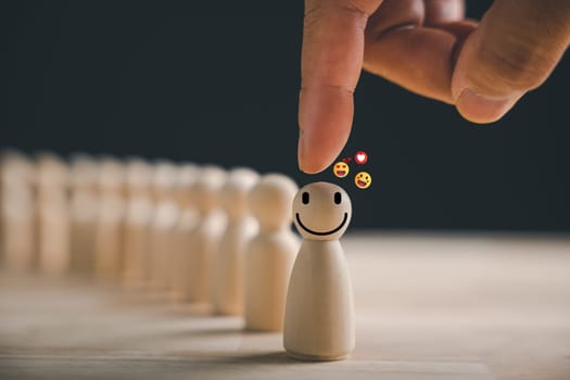 Hand picked wooden figure with a happy face in a crowd. Customer service rating and feedback survey. HR management chooses a positive attitude to lead the team towards success in the business concept.