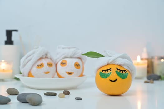 Orange fruits with towel and patches under eyes. Spa treatment and self care concept.