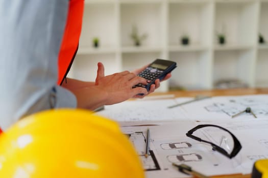 engineers discuss building on blueprint drawing using calculator