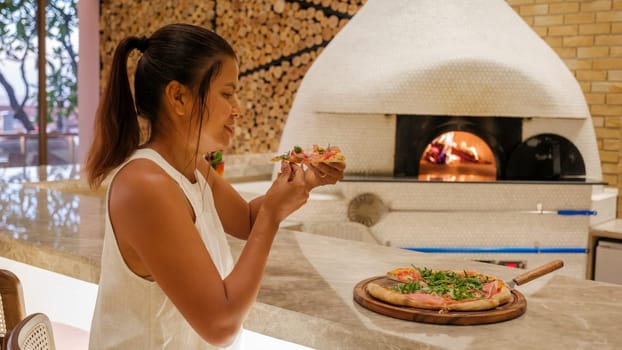 Asian woman eating a pizza in a restaurant, close up of a pizza dinner in an Italian restaurant in Thailand