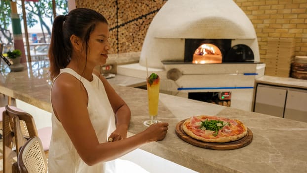 Asian woman eating a pizza in a restaurant, close up of a pizza dinner in an Italian restaurant in Thailand