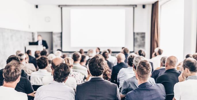 Speaker giving a talk in conference hall at business event. Audience at the conference hall. Business and Entrepreneurship concept. Focus on unrecognizable people in audience.