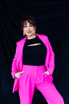 fashionable woman in bright clothes poses on a black background