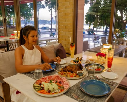 Asian woman having dinner in an Italian restaurant in Thailand