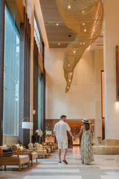 a couple of men and a woman walking in a hotel lobby of a luxury hotel in Thailand