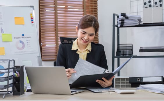 Businesswoman uses laptop to do finance, mathematics on wooden table in office and business background, tax, accounting, statistics and analytical research concept..