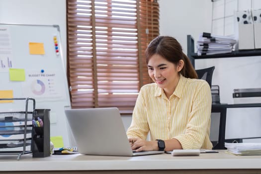 Businesswoman uses laptop to do finance, mathematics on wooden table in office and business background, tax, accounting, statistics and analytical research concept..