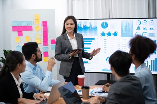 Young asian businesswoman presenting data analysis dashboard on TV screen in modern meeting. Business presentation with group of business people in conference room. Concord