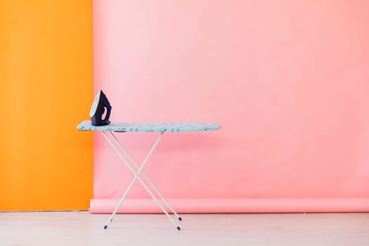 an ironing board with iron on pink background