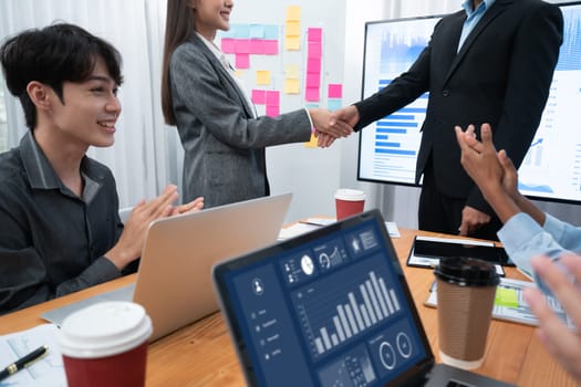 Diverse coworker celebrate with handshake and teamwork in corporate workplace. Happy business people united by handshaking after successful meeting or business presentation on data analysis. Concord