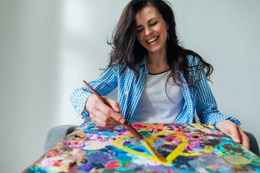 woman artist in blue clothes draws with brush on canvas