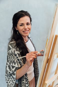 woman artist paints on white canvas at brown flower