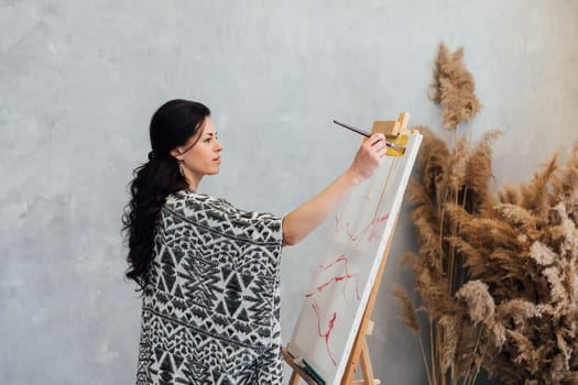 a woman of art russ painting on a white canvas on an easel