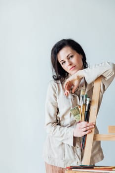 woman artist stands at an easel with tassels