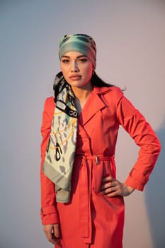 woman in a headscarf in an orange dress stands indoors