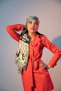 woman in a headscarf in an orange dress stands indoors