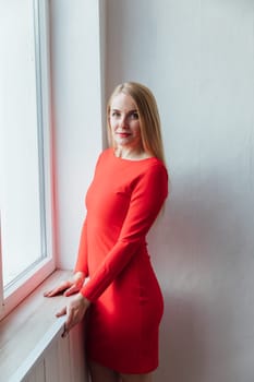a beautiful blonde woman standing at the window in the room