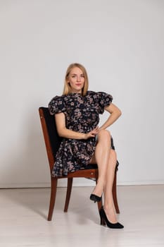 beautiful blonde sitting on a chair in bright room on a white background