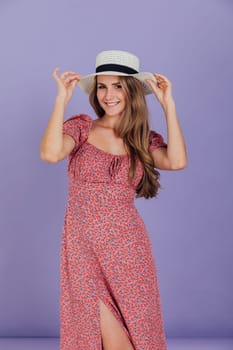 a blonde woman in a dress in a room wearing a hat on a purple background