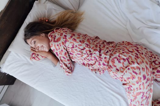 woman in sleeping clothes sleeps on a pillow in a bed in the bedroom