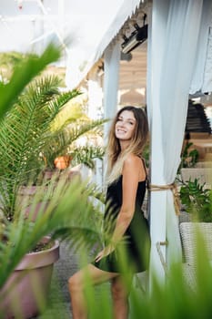 a woman in a black dress stands by the veranda in a restaurant on the street