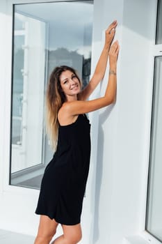 woman stands against a white wall with her hands on top of the windows