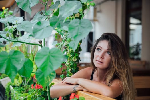 woman sits in a restaurant on a veranda outside waiting for food