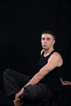 man in dark clothes sits in a dark room