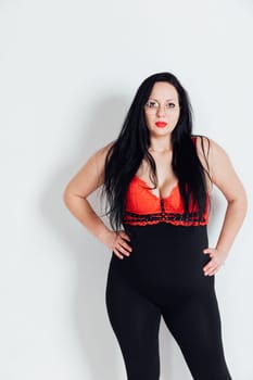 fat woman standing against a white wall in a room