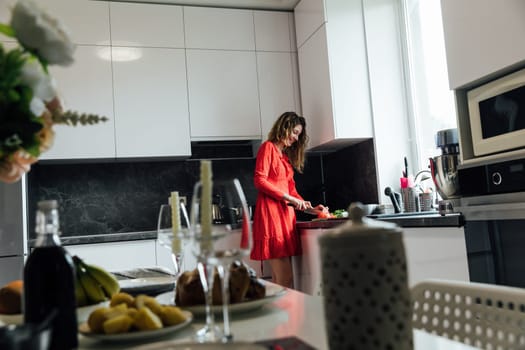 woman in a red dress prepares a salad for dinner table