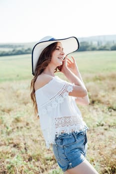 woman in a white hat stands on a dry field