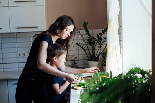 mother with a boy's child is preparing a salad in the kitchen