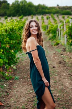 woman from the village in a green dress stands in a vineyard