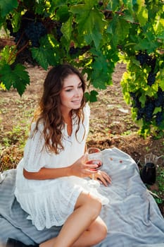 woman sitting by a grape with a glass of red wine