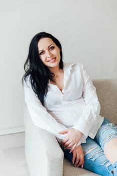 woman in a free style sits in a room on a sofa