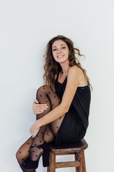 woman in black clothes and black tights sits posing on a chair