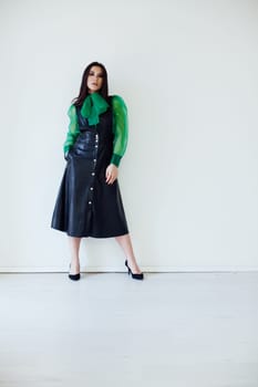 fashionable woman brunette beautiful standing against a white wall in green shirt