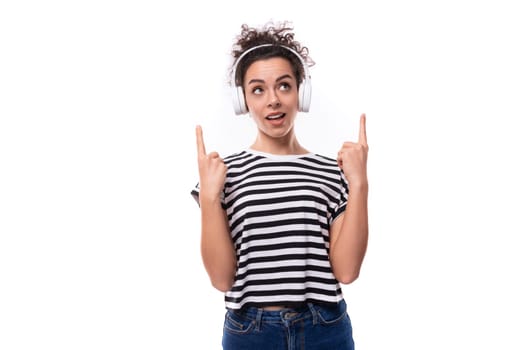 young well-groomed curly woman with black hair in a summer t-shirt with white wireless headphones.